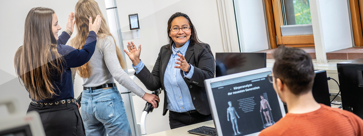 Professorin erläutert Studierenden in einem Labor eine Körperanalyse.