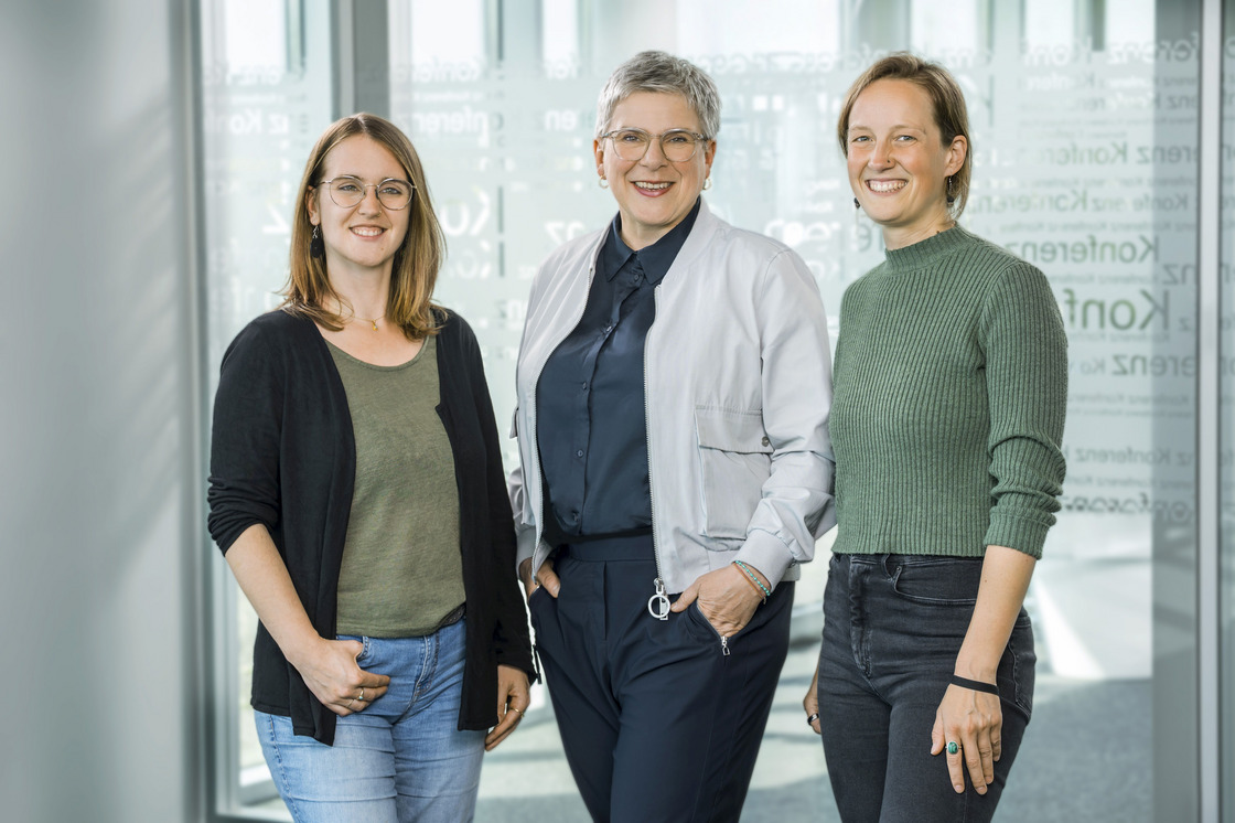 Drei weiblich gelesene Personen stehen nebeneinander in einem modernen, lichtdurchfluteten Bürogebäude und lächeln in die Kamera. Links steht Berit Blawert (Referentin für Chancengerechtigkeit), in der Mitte Prof. Dr. Susanne Düchting (Vizepräsidentin für Chancengerechtigkeit und Nachhaltigkeit) und rechts Lea Klöppel (Referentin für Nachhaltigkeit).